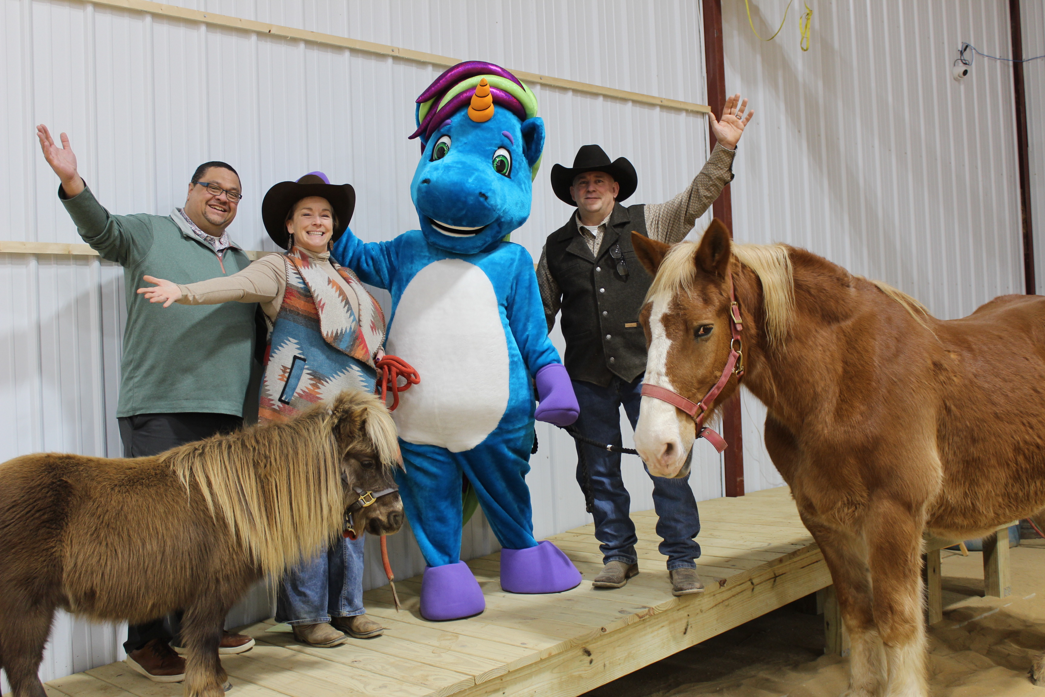 Pictured (from left): DCDL Director Bryan Howard, Stockhands Director of Development Angie Mack, DCDL Mascot Percy Unicorn, Stockhands Executive Director Tim Funk; Horses Winston and Mac.