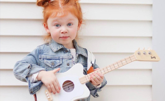 Kid-Standing and holding a Loog Guitar
